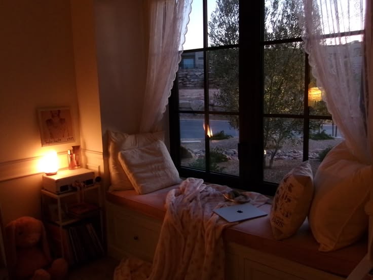 A softly lit window seat with a blanket at dusk